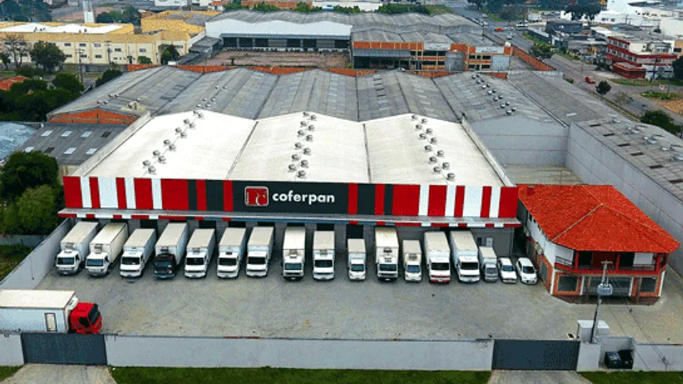 Vista aérea da sede da Coferpan em Curitiba, com a frota de caminhões estacionada em frente ao galpão