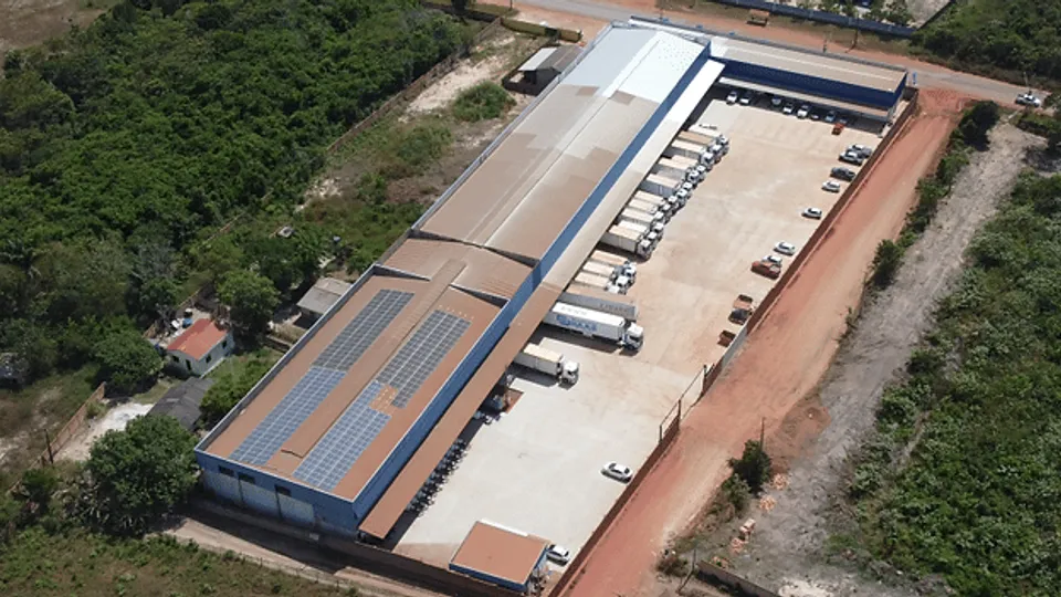 Vista aérea do centro de distribuição da MASA, com carretas nas docas e placas solares no telhado do galpão