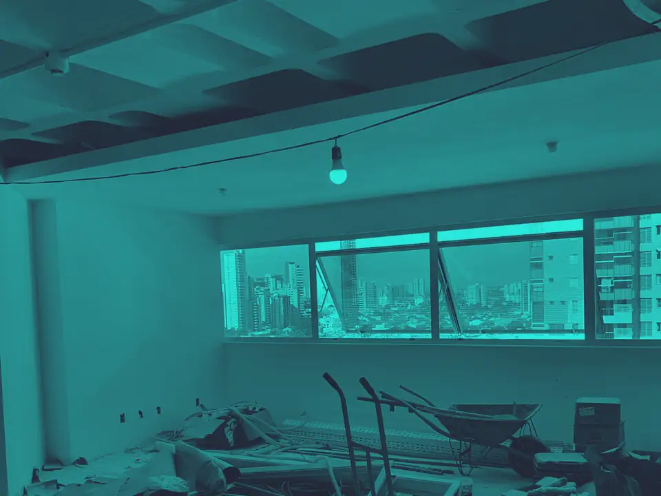 Sala em obra no Walk Bueno Business, com material de construção no chão e a vista da cidade pela janela