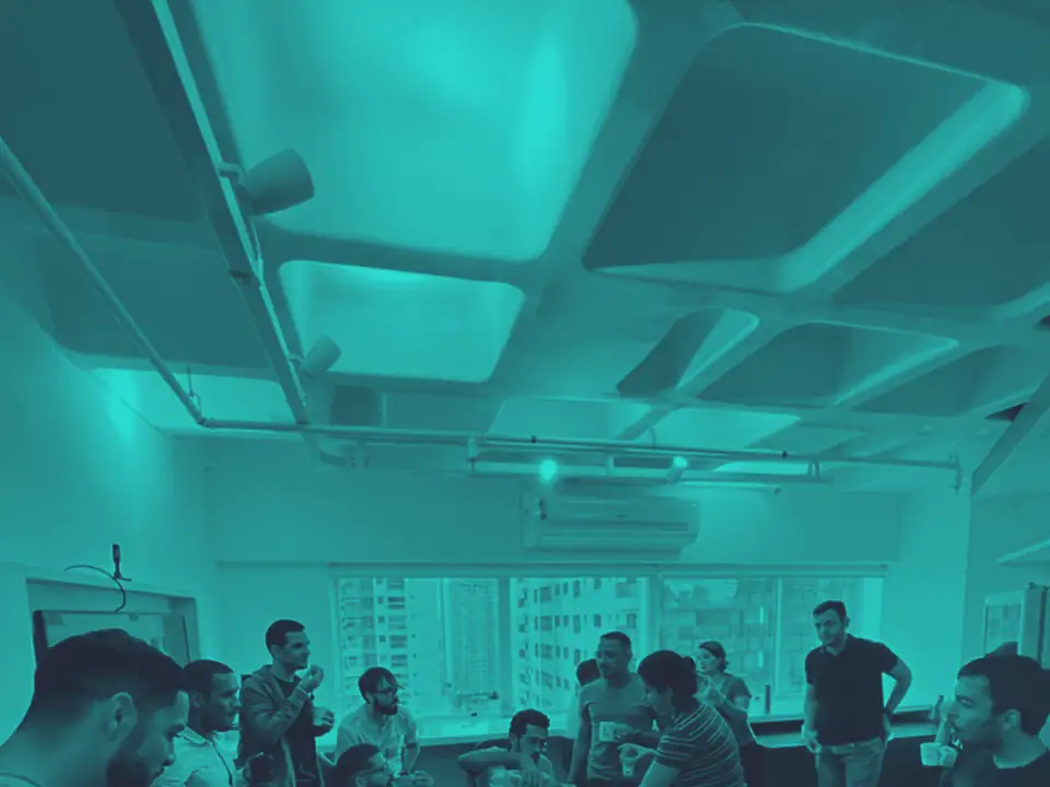 Time reunido em círculo em volta de uma mesa na sede, em um dos encontros da equipe